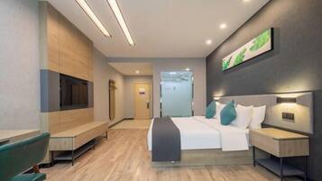 Una habitación de hotel moderna con cama, mesitas de noche, un banco y televisor de pared.