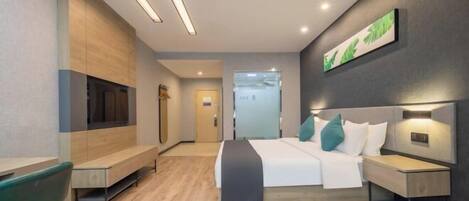 A modern hotel room with a bed, bedside tables, a bench, and a wall-mounted TV.