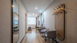 Une chambre d’hôtel avec un long couloir, un coin repas et un porte-manteau.