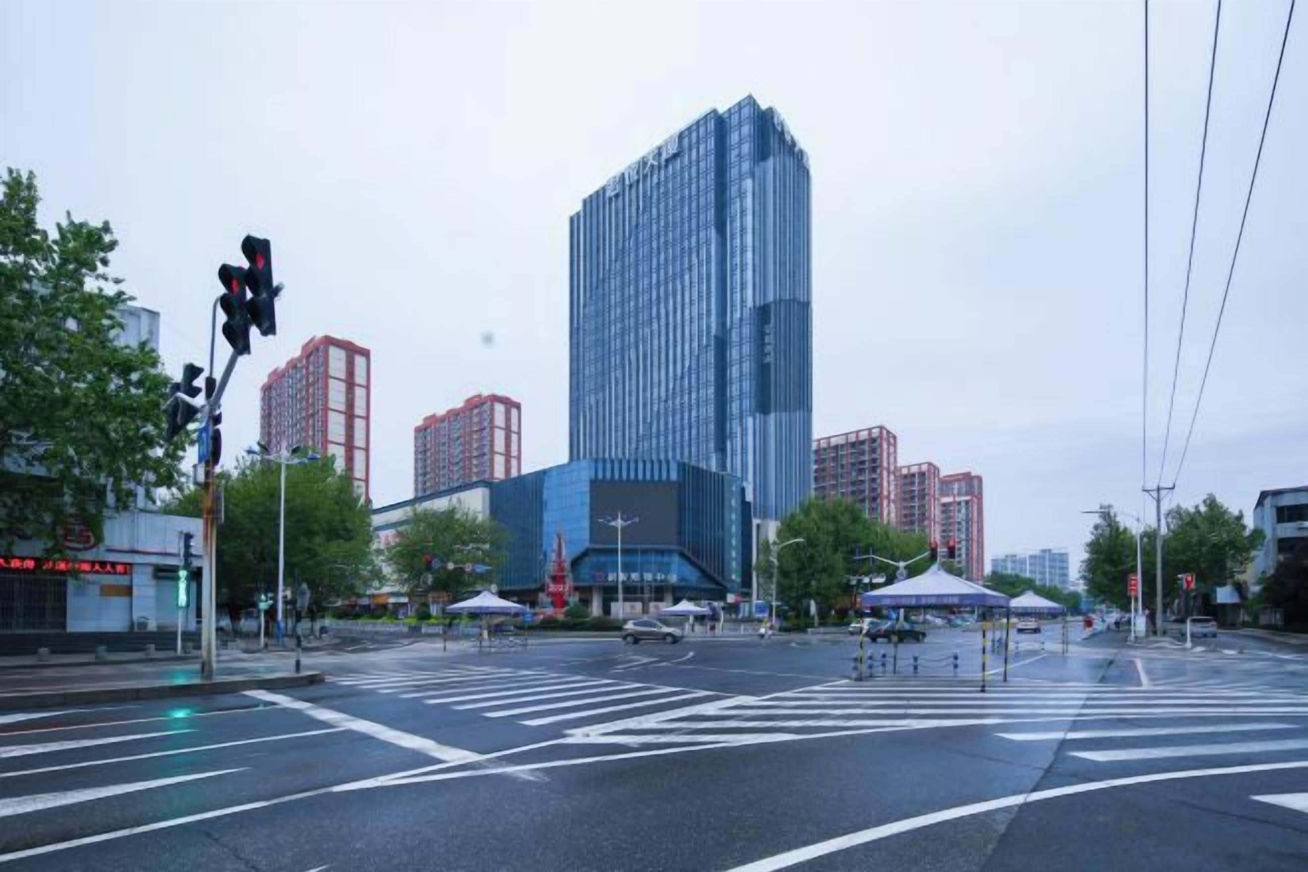 A city intersection with a modern building, crosswalks, and traffic lights.
