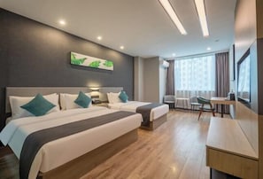 Ein Hotelzimmer mit zwei Betten, einem Schreibtisch, einem Stuhl und einem großen Fenster.