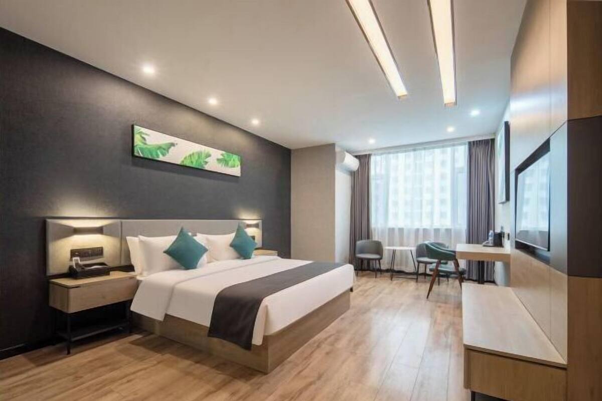 Una habitación de hotel moderna con una cama grande, mesitas de noche, un escritorio y un televisor.