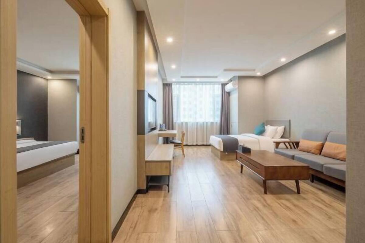 Una habitación de hotel moderna con una cama, un escritorio, un sofá y una mesita de centro.