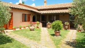 Ein traditionelles Haus im mediterranen Stil mit Ziegeldach, einem zentralen Innenhof mit Kübelpflanzen und einem gepflasterten Weg.