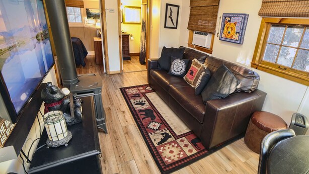 A cozy living room with a leather sofa, a fireplace, and a television. - 2 Bedroom with Great View from Wrap-Around Deck (Estes Park)