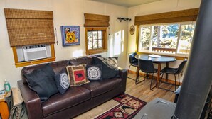A cozy living room with a brown leather sofa, a patterned rug, and a wood-burning stove. - 2 Bedroom with Great View from Wrap-Around Deck (Estes Park)