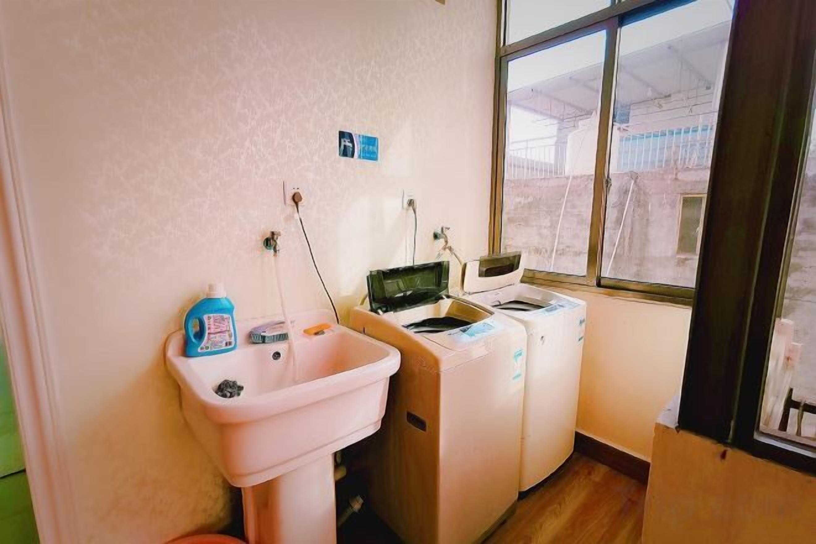 Quarto pequeno com pia, máquina de lavar e janela.