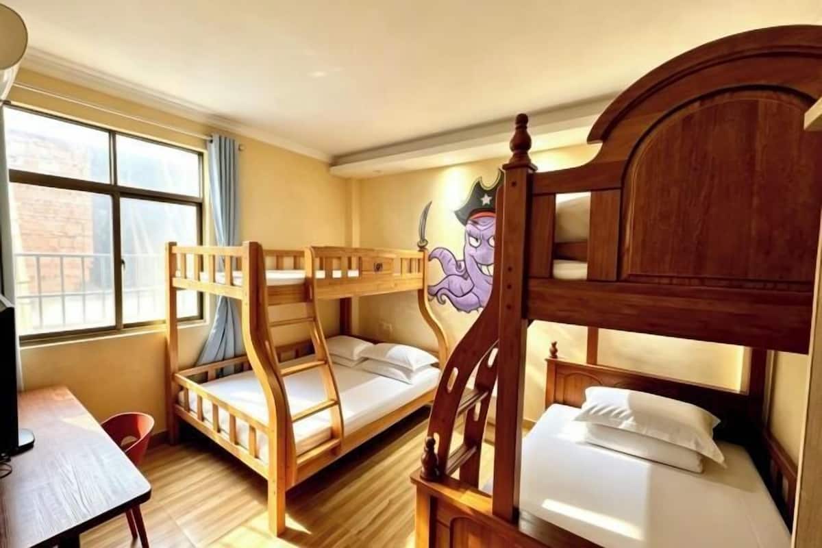 A room with bunk beds, a desk, a chair, a window with curtains, and a wall mural.