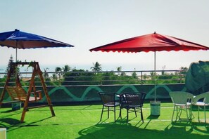 A patio with a swing set, two umbrellas, and outdoor seating. - Beihai Bishuiwan Homestay (Beihai Silver Beach) (Beihai)