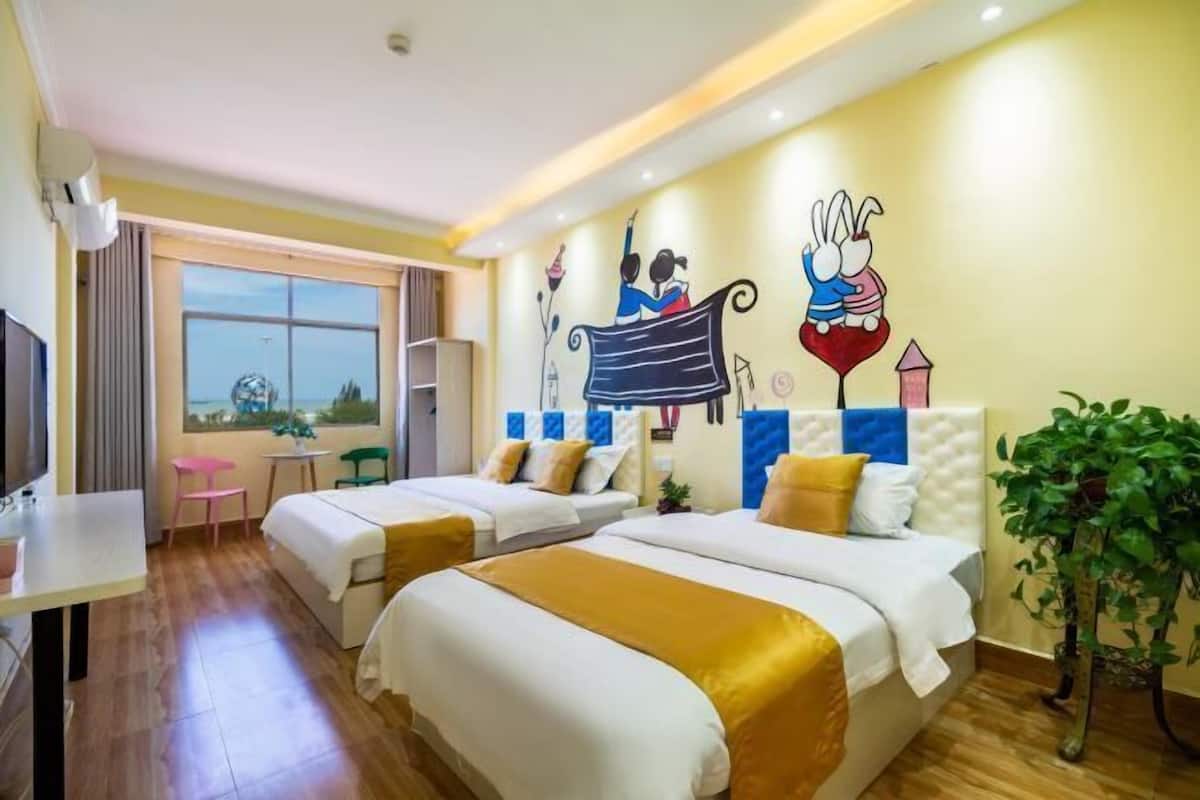 A hotel room with two beds, a TV, a small table, a chair, a window, and a wall mural.