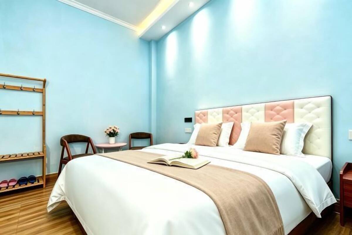 A neatly arranged bedroom with a bed, bedside tables, a shoe rack, and a small table with a flower.