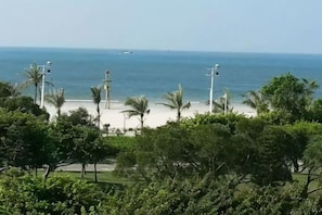 A beach view with palm trees, a clear sky, and a distant boat. - Beihai Bishuiwan Homestay (Beihai Silver Beach) (Beihai)