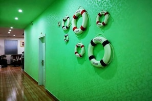 A hallway with green walls and wooden flooring, featuring life rings on the wall. - Beihai Bishuiwan Homestay (Beihai Silver Beach) (Beihai)