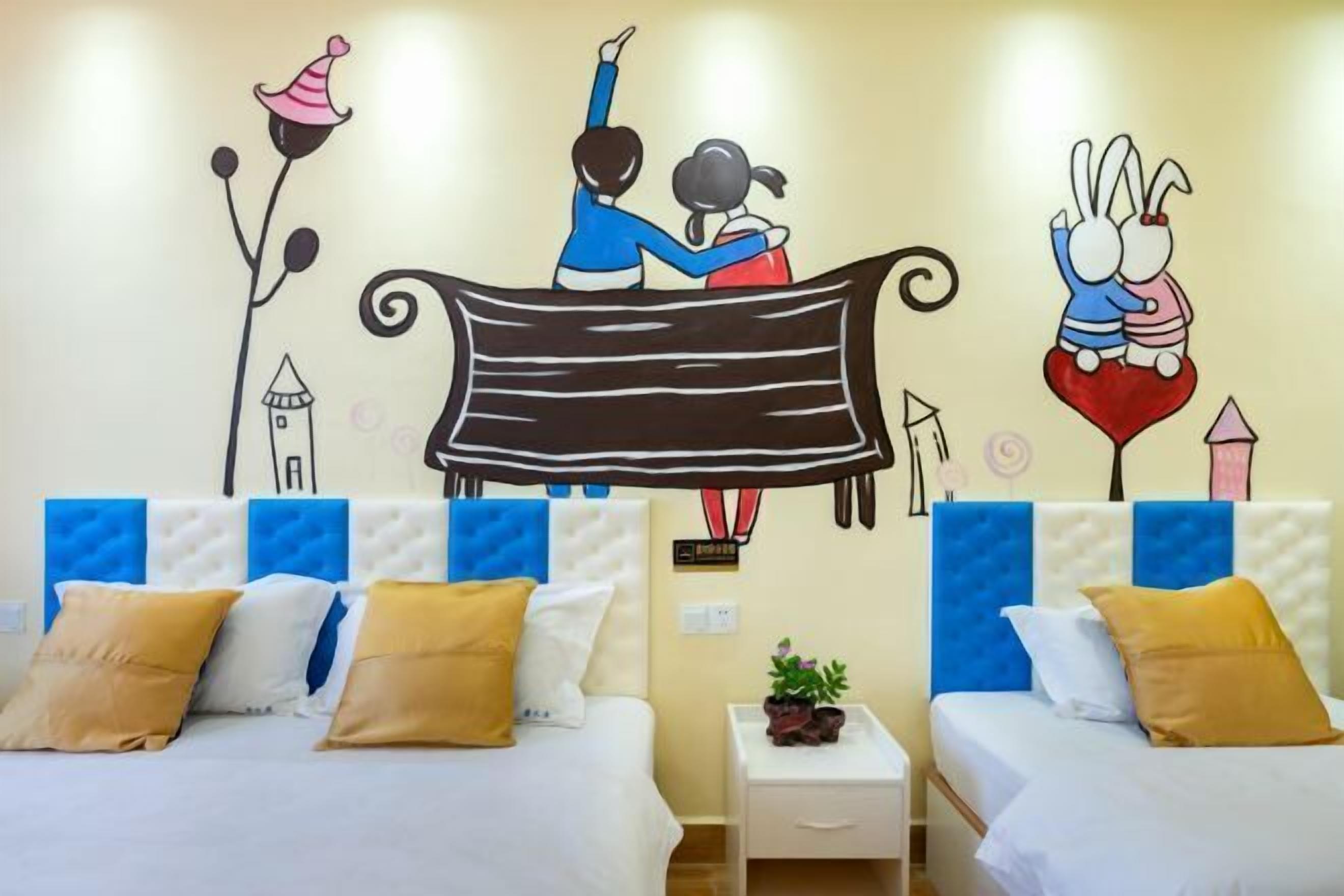 Habitación de hotel con dos camas, cada una con cabecero y almohadas. Se observa una mesita de noche pequeña con una planta encima.