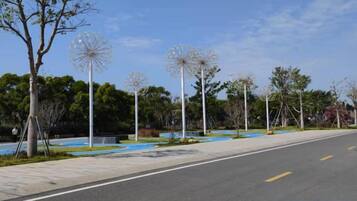 Una calle pavimentada con aceras, árboles y estructuras esféricas decorativas.