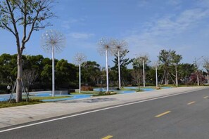 A paved road with a sidewalk, trees, and decorative spherical structures. - Beihai Bishuiwan Homestay (Beihai Silver Beach) (Beihai)