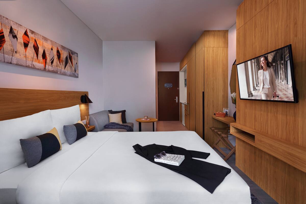 Une chambre d’hôtel moderne dotée d’un grand lit, d’un téléviseur fixé au mur et d’un décor avec des panneaux en bois.