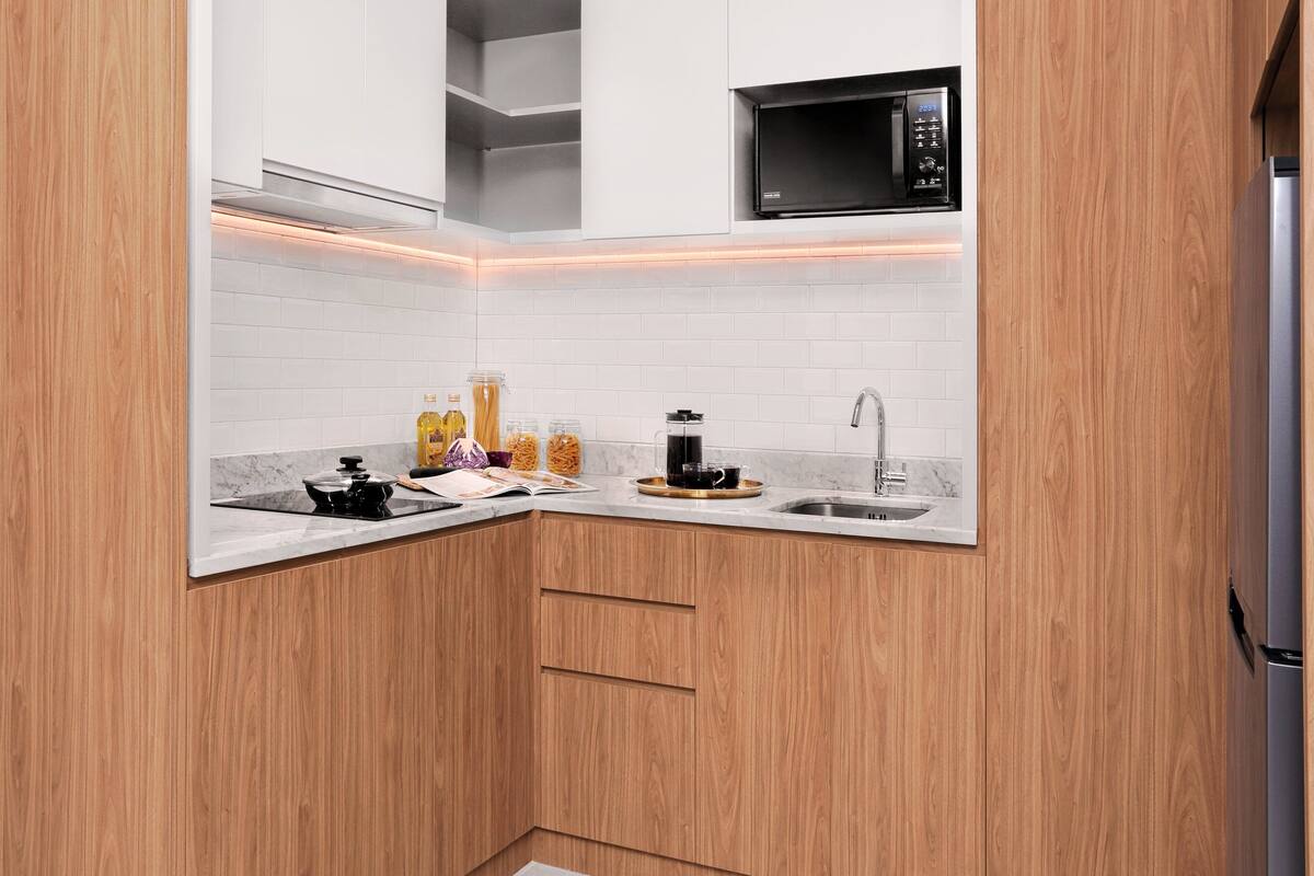 Une cuisine moderne avec des meubles en bois, un évier en acier inoxydable et un micro-ondes noir.