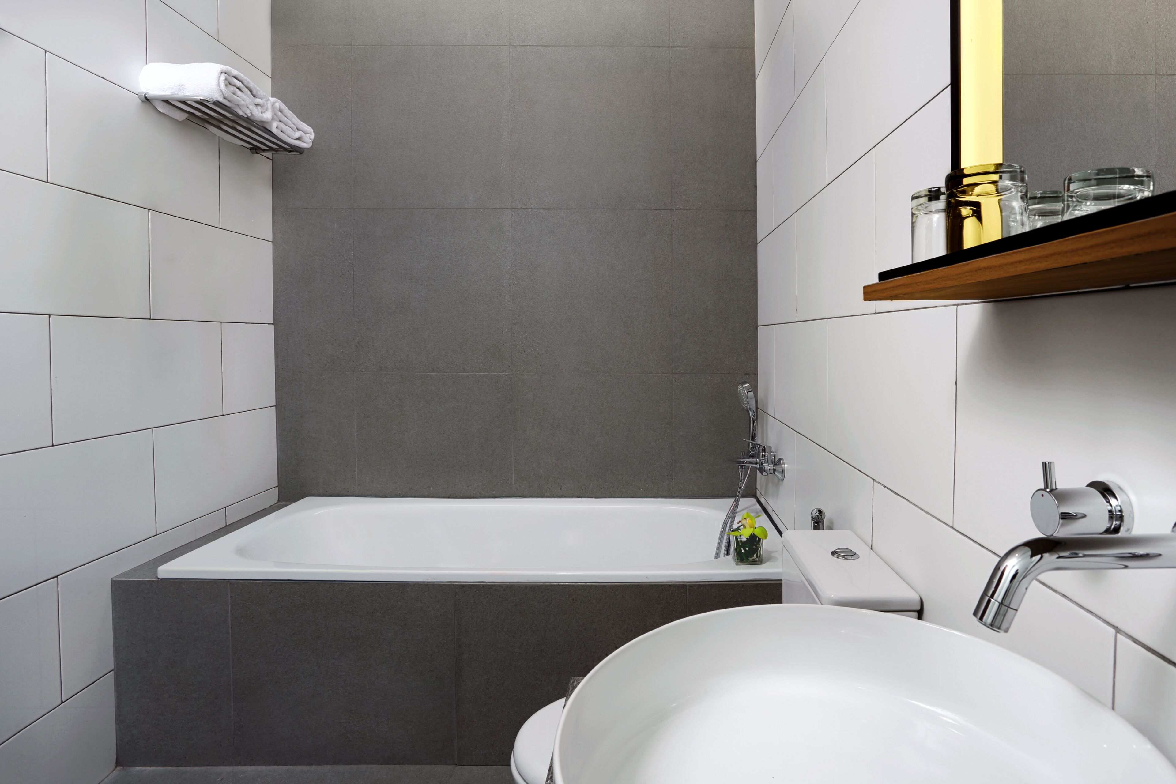 Un baño moderno con bañera, lavamanos y un estante con artículos de aseo.