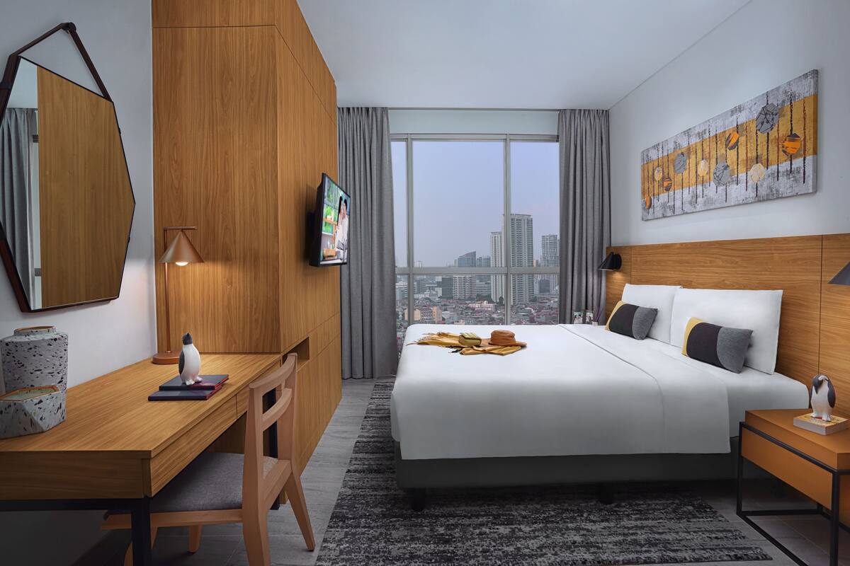 Une chambre d’hôtel moderne dotée d’un grand lit, d’un bureau, d’une chaise, d’une télévision et offrant une vue sur la ville.