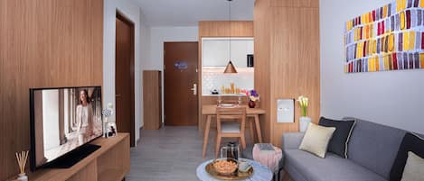 Una sala de estar moderna con televisor, sofá, mesa de centro y armarios de madera.