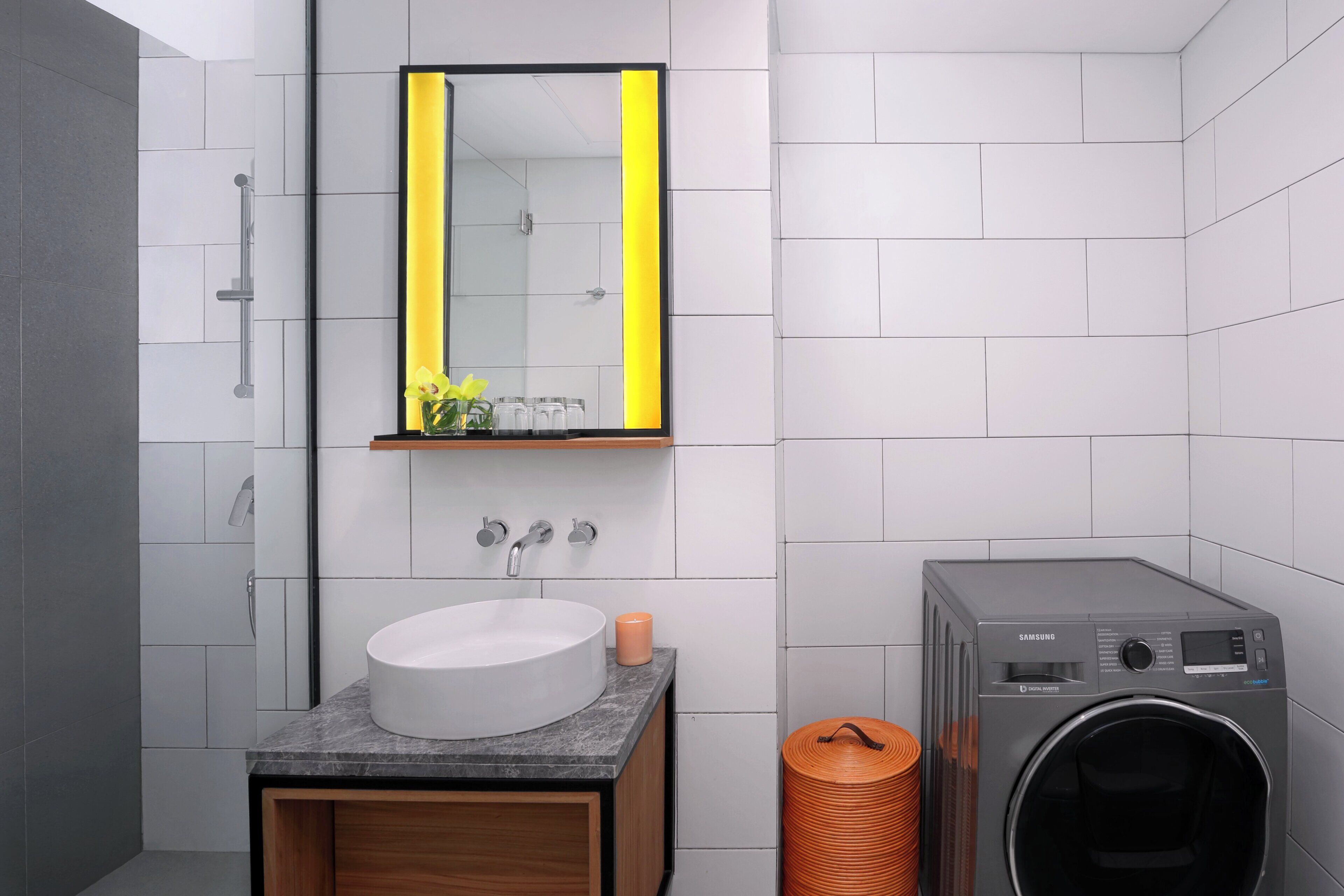 A modern bathroom with a sink, mirror, and washing machine.