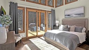 Un dormitorio con una cama grande, vistas al exterior a través de puertas corredizas de vidrio y un ventilador de techo.