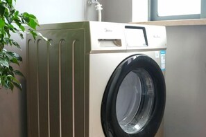 A front-loading washing machine with a control panel and a door, mounted on a wall. - Xinjiayuan Hotel (Yizhang)