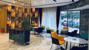 A modern hotel lobby with a central seating area, a decorative partition, and a view of the street. - Xinjiayuan Hotel (Yizhang)