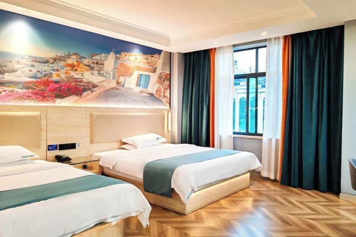A hotel room with two beds, a large mural, and a window with curtains.