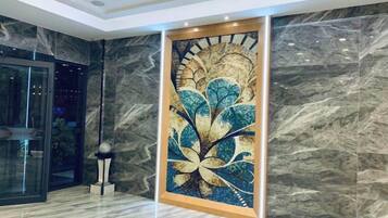 A lobby with a large abstract mural, marble walls, and a glass elevator.