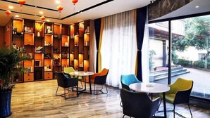 A modern interior with a large bookshelf, a round table, and chairs. - Xinjiayuan Hotel (Yizhang)