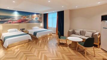 A hotel room with two beds, a sofa, a dining table, and a mural of a coastal scene.