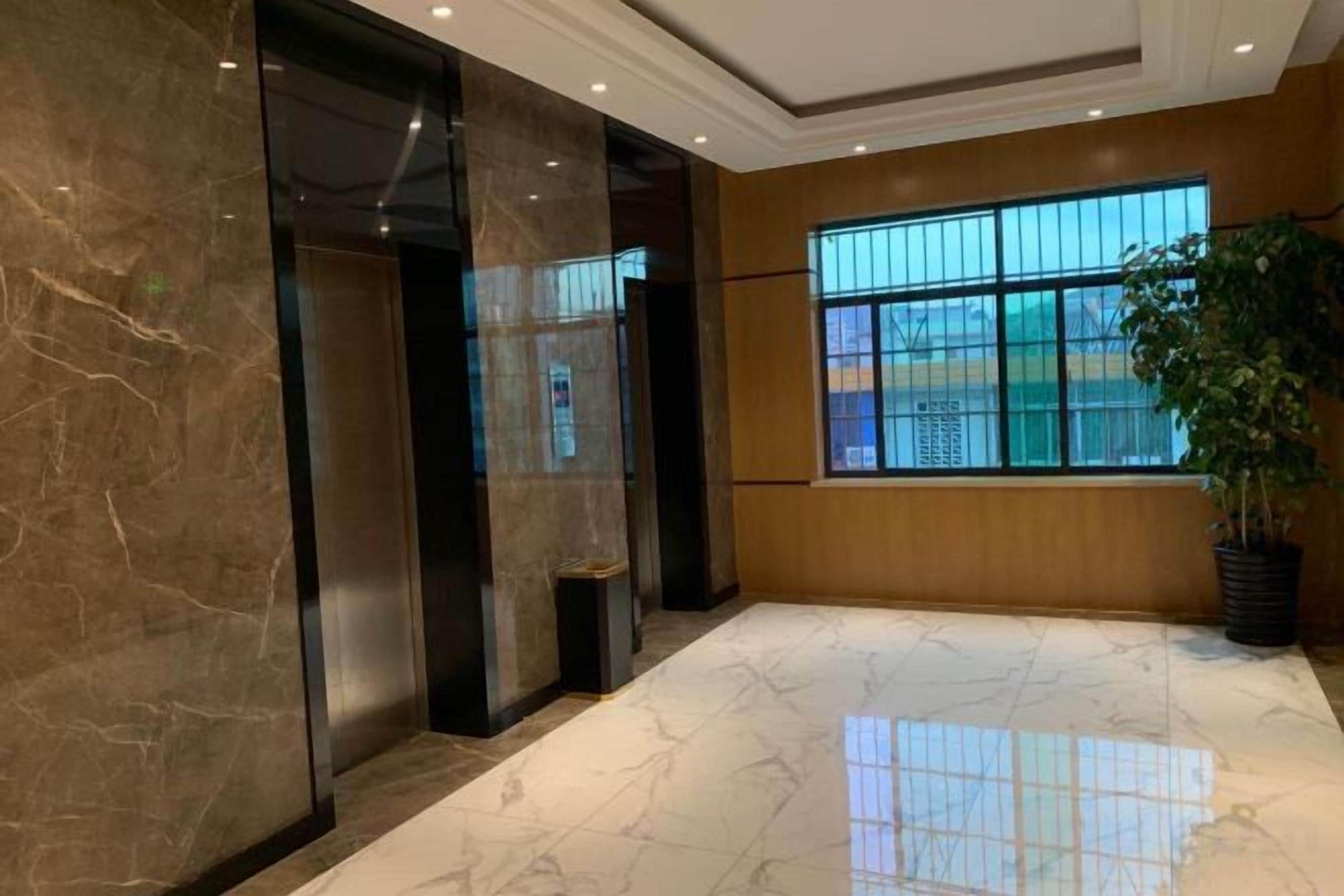 A lobby with marble flooring, a large window, and a potted plant.
