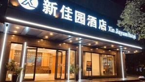 The exterior of Xin Jiayuan Hotel with illuminated signage, large glass doors, and a modern architectural design. - Xinjiayuan Hotel (Yizhang)