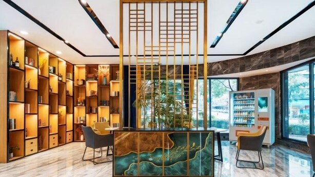A modern lobby with a central seating area, bookshelves, and a vending machine. - Xinjiayuan Hotel (Yizhang)