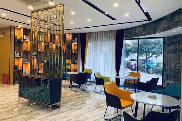 A modern hotel lobby with a central seating area, a decorative partition, and a view of the outdoors.