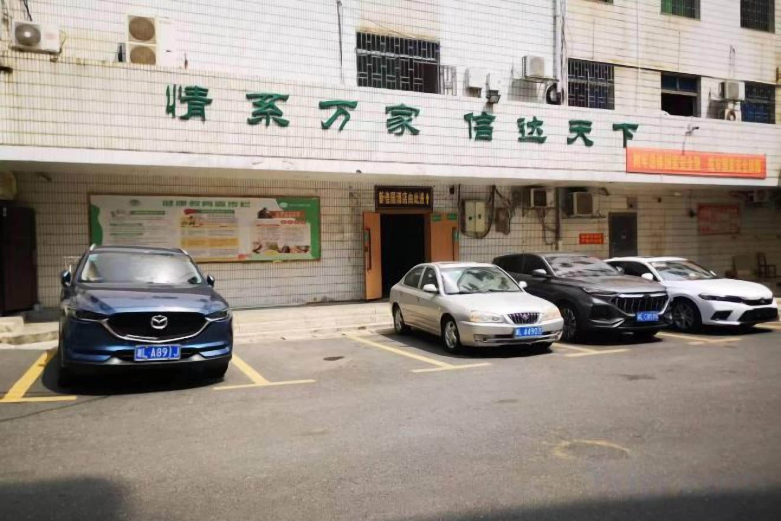 Un edificio con un letrero que dice 'Hotel' y un estacionamiento con varios autos.