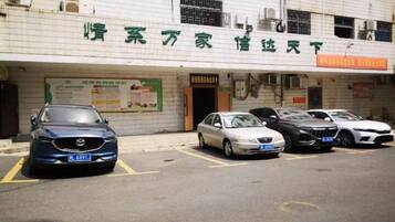 Un edificio con un letrero que dice 'Hotel' y un estacionamiento con varios autos.