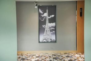 A framed picture of the Eiffel Tower on a wall, a patterned floor, and a door with a sign. - Xinjiayuan Hotel (Yizhang)