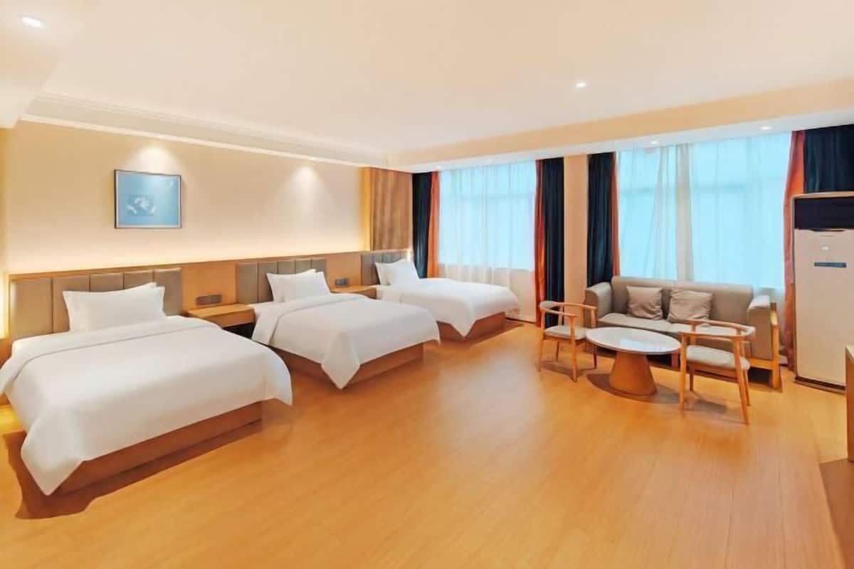 A hotel room with two beds, a sofa, a coffee table, and a TV.