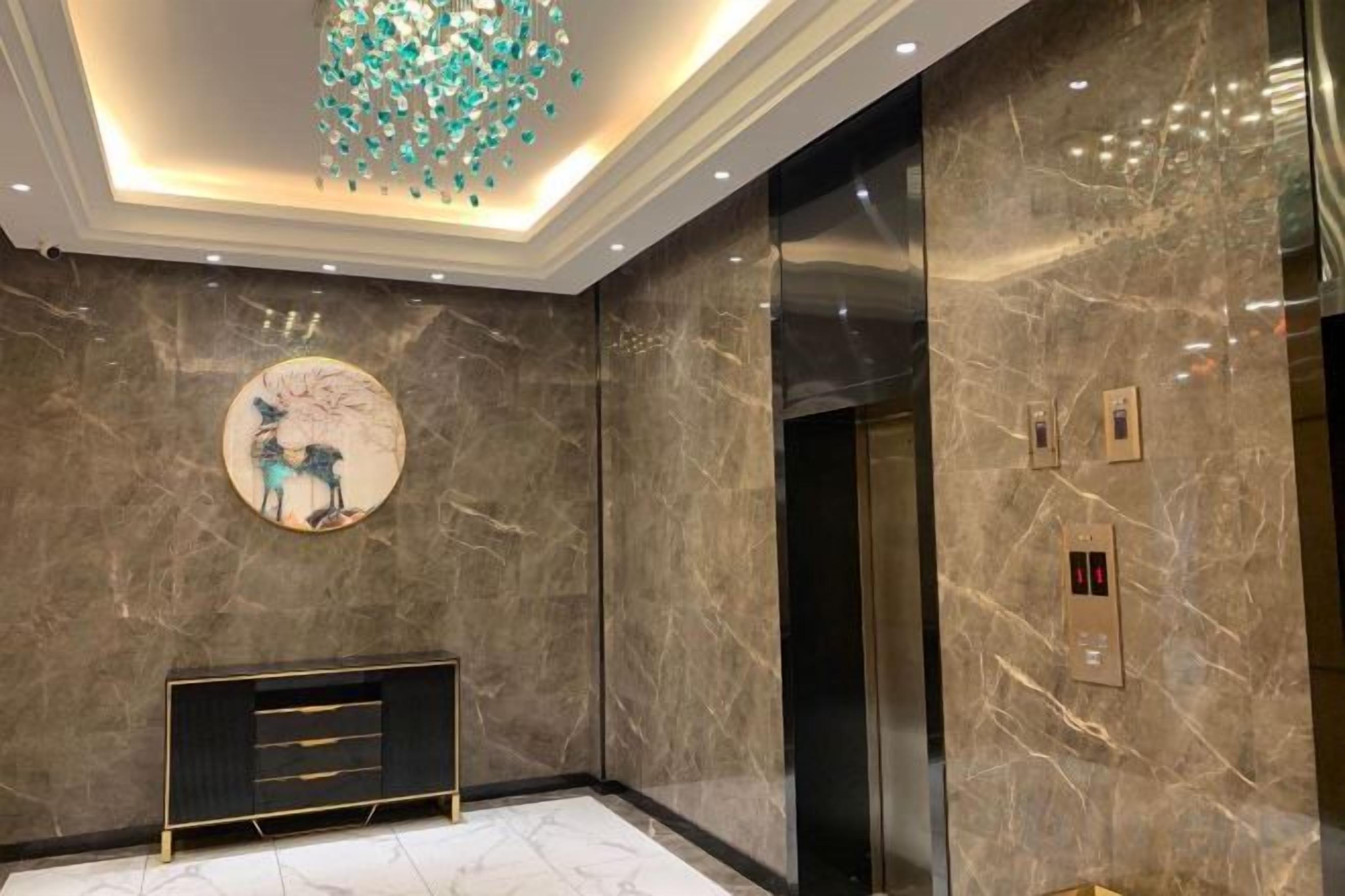 A modern elevator with a marble wall and a circular artwork above it.