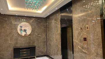 A modern elevator with a marble wall and a circular artwork above it.