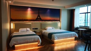 A hotel room with two beds, a large mural of the Eiffel Tower, a small table, and a chair. - Xinjiayuan Hotel (Yizhang)