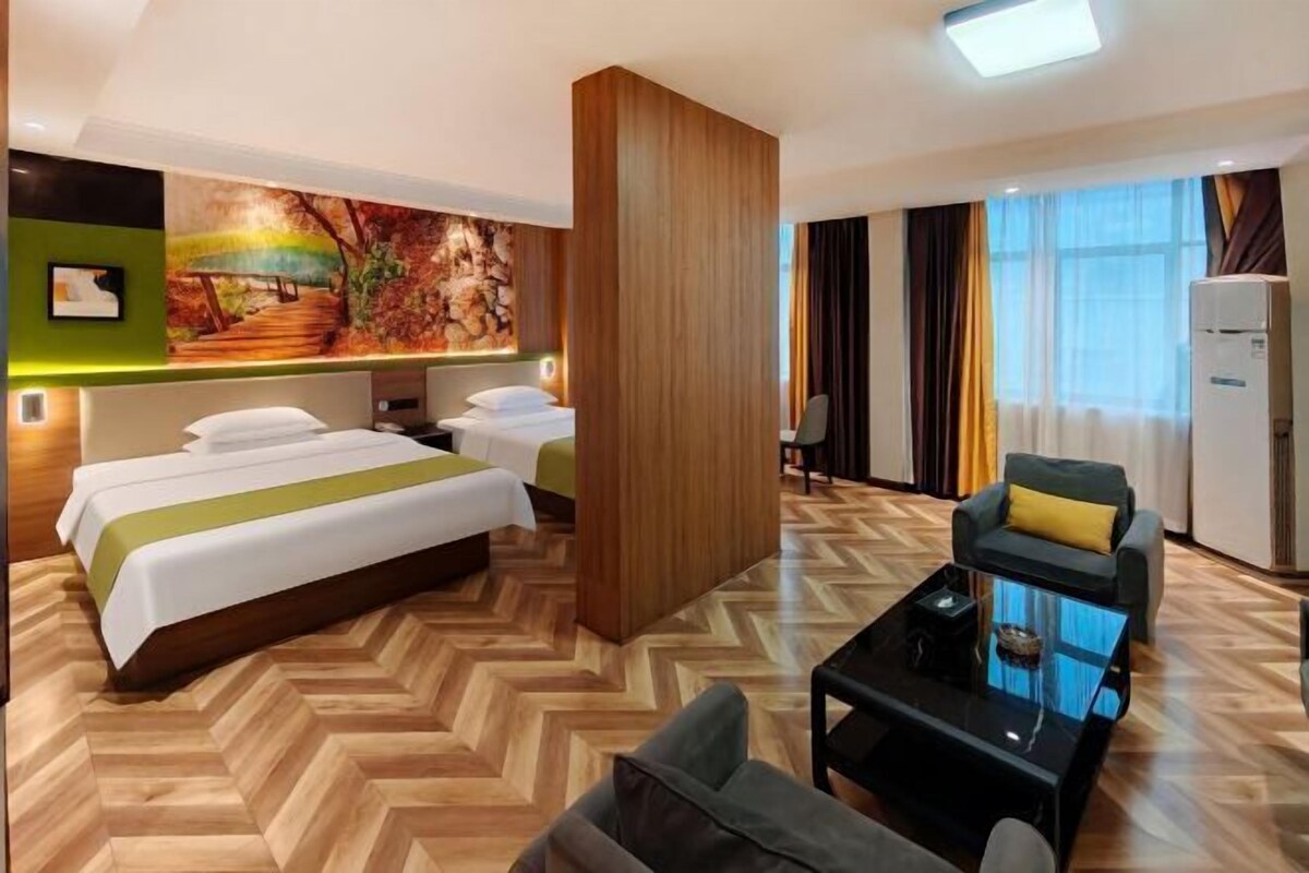 A hotel room with a large bed, a sofa, a coffee table, and a painting on the wall.