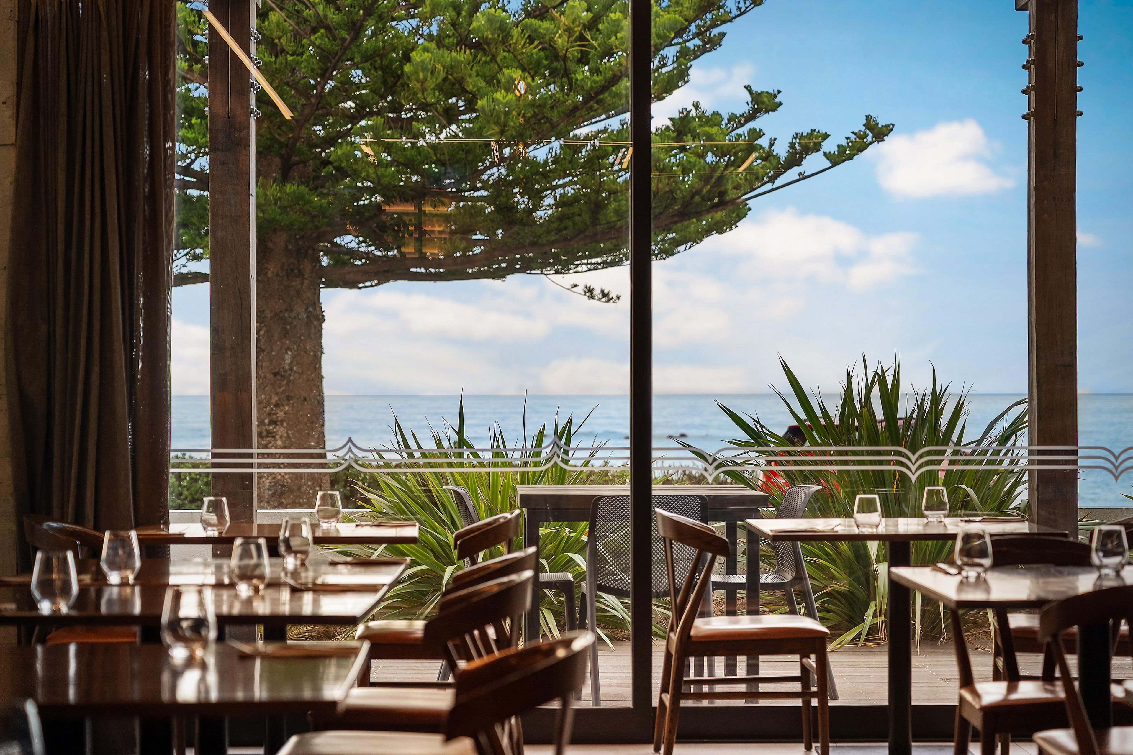 An outdoor dining area with tables and chairs, overlooking a body of water.