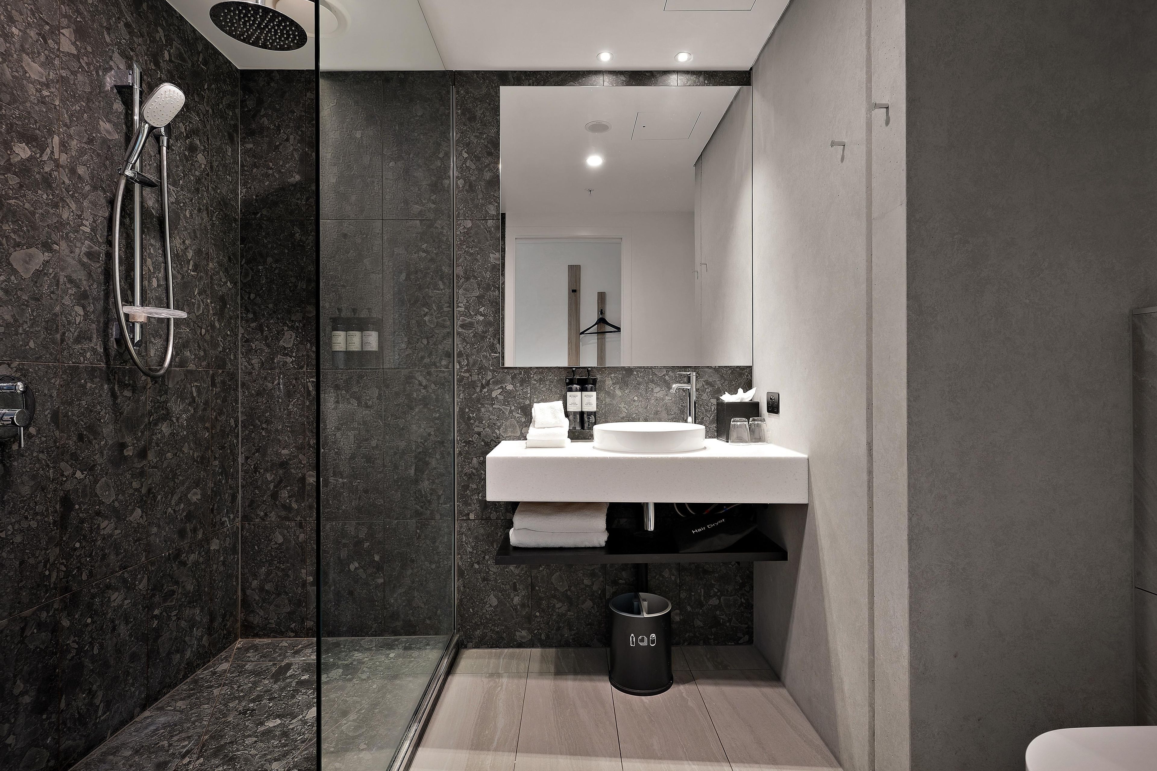 A modern bathroom with a glass-enclosed shower, a white sink, and a mirror above it.