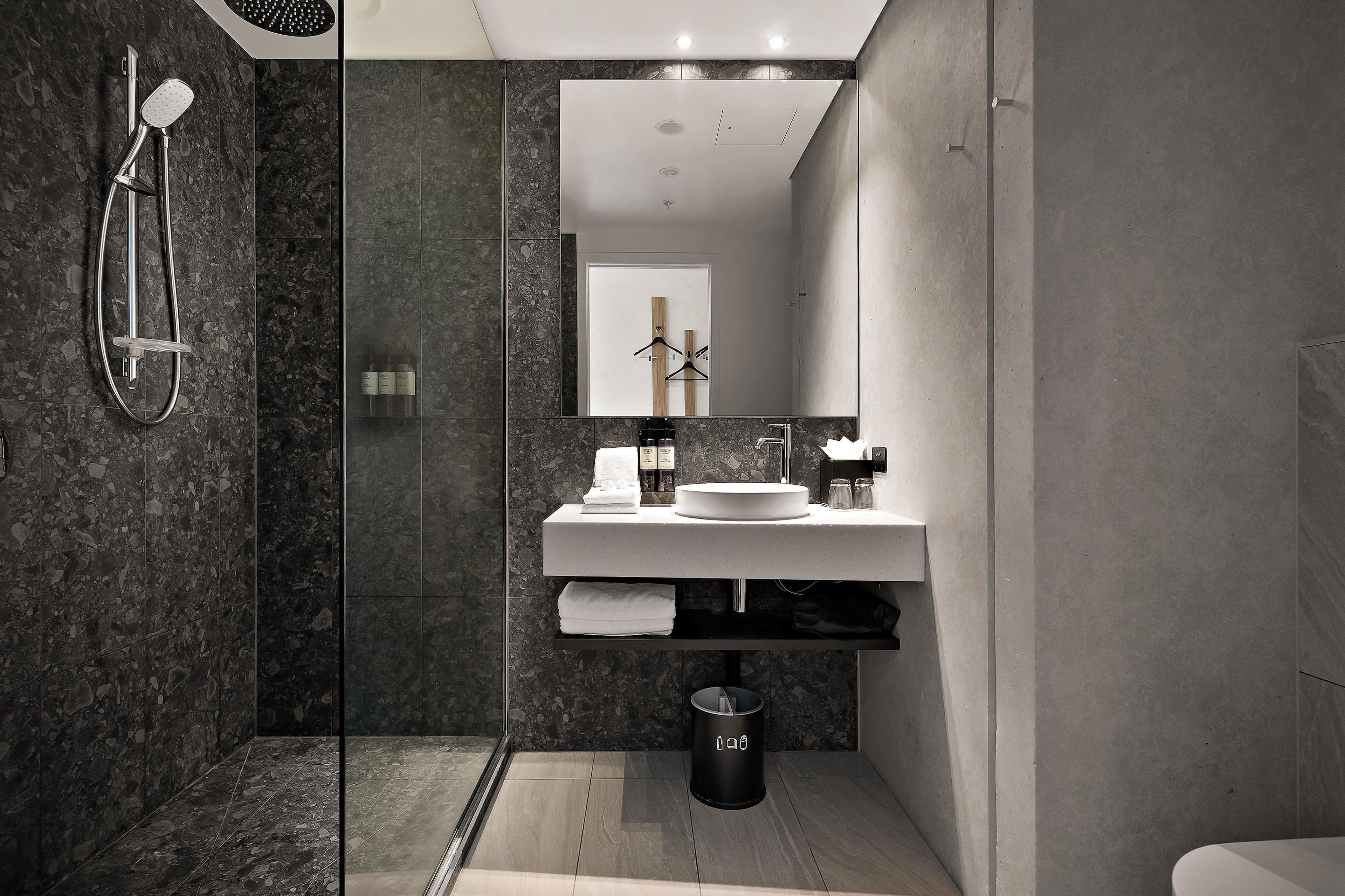 A modern bathroom with a glass-enclosed shower, a white sink, and a mirror above it.
