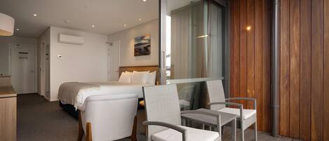 Ein Hotelzimmer mit einem Bett, zwei Stühlen, einem Schreibtisch und einem großen Fenster.