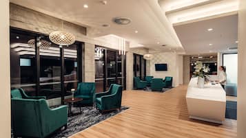 A modern lobby with teal armchairs, a reception desk, and large windows.